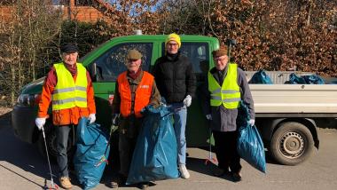 Die 4 Mitglieder in voller Müllsammelmontur vor einem Auto der Stadt
